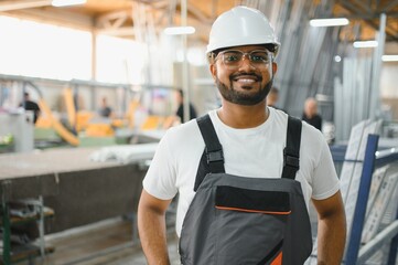 Smiling and happy indian employee. Industrial worker indoors in factory. Young technician with...