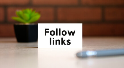 Follow links text of business concept on white list and with pen and a black pot with a flower behind