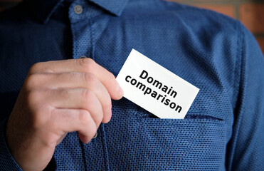 Domain comparison text on a white sign in the hand of a man in shirt