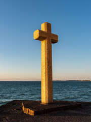 Christian stone cross facing the sea at sunset, Saint-Malo, Brittany, France.