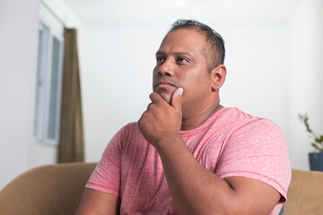A man in a red shirt is sitting on a couch and looking at the camera