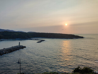 Sunset over tranquil bay with lighthouse guiding ships home © larrui