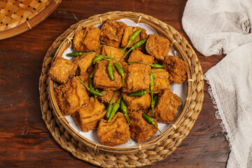 Crispy golden Tahu Sumedang topped with fresh chilies, served on woven tray. Classic Indonesian snack.