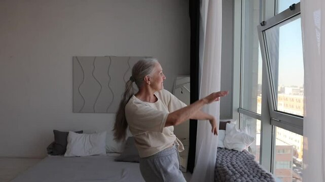 senior woman  listens to music and dances at home in the morning. seniors llifestyle. International Music Day. dopamine hobbies