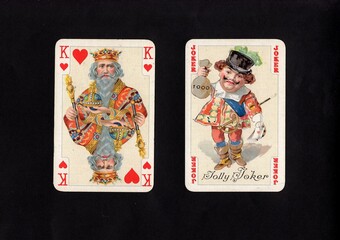 A pair of vintage playing cards featuring a joker isolated on a black background.