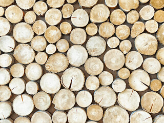 The arrangement of stacked wooden logs showcases their unique natural patterns and textures, making...