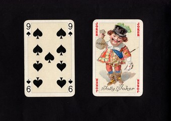 A pair of vintage playing cards featuring a joker isolated on a black background.