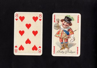 A pair of vintage playing cards featuring a joker isolated on a black background.
