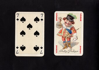 A pair of vintage playing cards featuring a joker isolated on a black background.