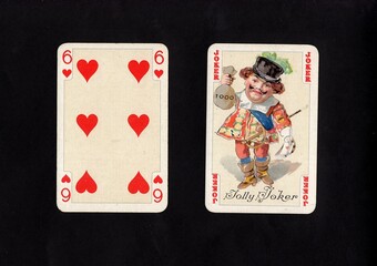 A pair of vintage playing cards featuring a joker isolated on a black background.