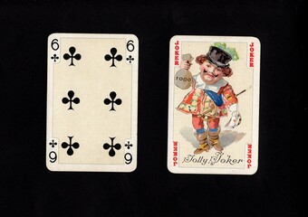 A pair of vintage playing cards featuring a joker isolated on a black background.