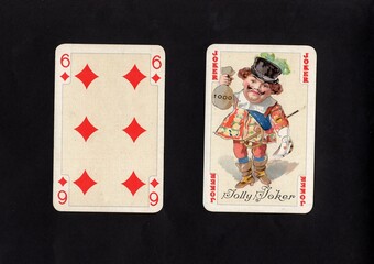 A pair of vintage playing cards featuring a joker isolated on a black background.