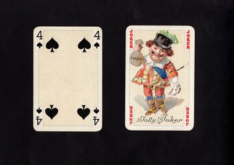 A pair of vintage playing cards featuring a joker isolated on a black background.