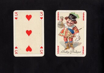 A pair of vintage playing cards featuring a joker isolated on a black background.