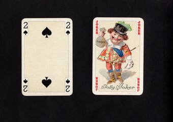 A pair of vintage playing cards featuring a joker isolated on a black background.