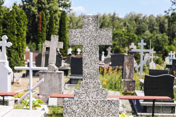 Gravestones and granite crosses. Peaceful cemetery with tombstones and greenery. Traditional Polish burial site. Memorial place of rest. Christian symbol of faith and remembrance.