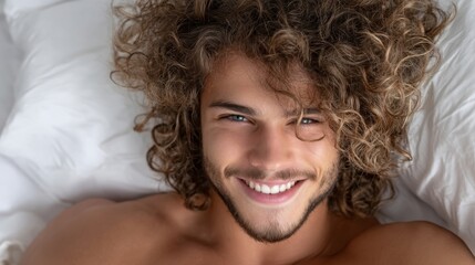 A man lies in bed, beaming with joy, surrounded by the comfort of soft white sheets on a serene morning