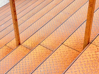 Detail of an external staircase made of rusty steel checker plate with rusted railing profiles