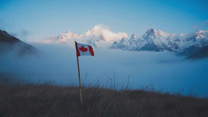 Canadian flag waving in mountainous landscape with misty valleys at sunrise.