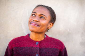 Thoughtful African young woman smiling and looking up