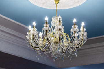 Luxurious crystal chandelier beautifully lit and hanging from an ornate ceiling.