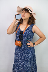 Beautiful young asian woman wearing blue summer dress and beach straw hat is disappointed while...