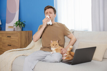 Man suffering from allergy with his cat on sofa at home