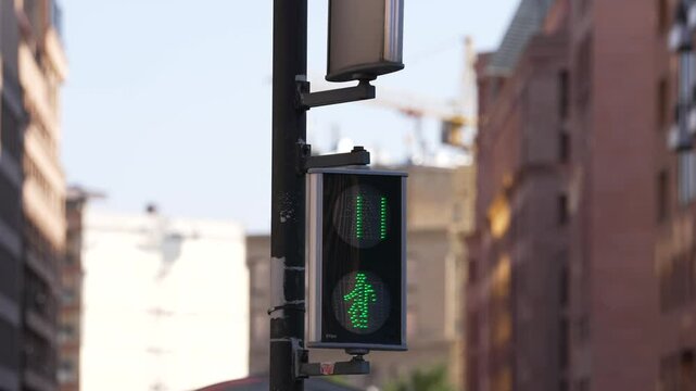 Pedestrian signal countdown in urban area.  Pedestrian traffic signal displays a countdown of sixteen seconds, indicating when it's safe for pedestrians to cross the street in a busy urban setting.