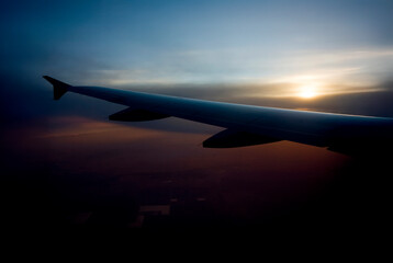 Silhouette of a ommercial airplane wing with a sunset background