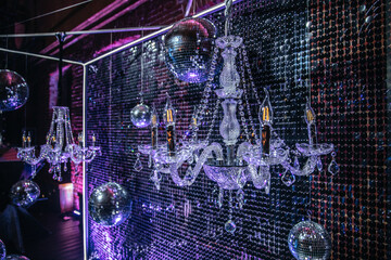 Crystal chandeliers paired with disco balls create a striking visual at a stylish event. The...