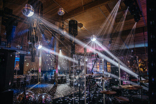 Vibrant event venue with a disco-themed dance floor, illuminated by disco balls and dynamic lighting. Music equipment set up, ready for a lively celebration or party event.