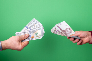 Hands exchanging Ukrainian Hryvnia for US Dollars. Two hands exchanging stacks of Ukrainian Hryvnia banknotes for US Dollar bills against a vibrant green background, currency exchange transaction