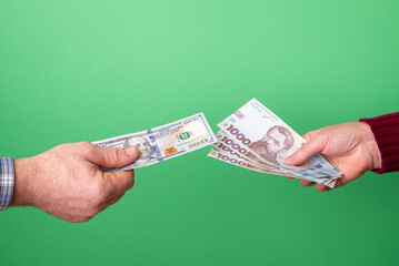 Currency exchange: man gives dollars, woman gives hryvnias. A man gives 100 US dollars while a...