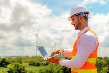 Handsome male wind energy technician engineer inspecting clean energy generating industrial...