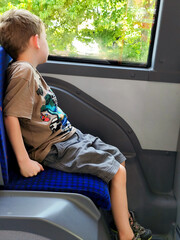 Junge schaut aus dem Busfenster – Kind beim Nachdenken während der Fahrt im öffentlichen Verkehr