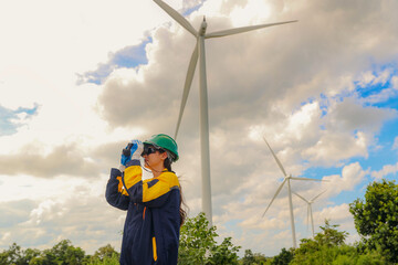 Female geographer in green safety helmet using binoculars surveying looking from distance working...