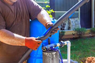 Contractor installs hoses connect to water well fittings on an irrigation system in backyard works day.