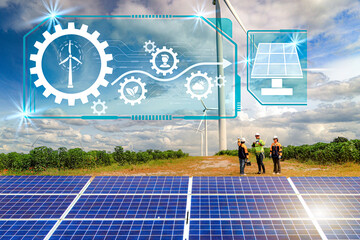 Male and female engineers in the field alternative energy inspect wind turbines in a farm area...