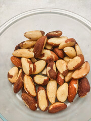 Brazil nuts filling a glass bowl on a marble countertop