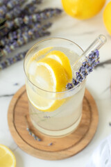 Refreshing lavender and lemon summer drink with sparkling water on white kitchen table.