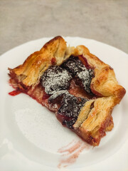 Delicious plum galette with icing sugar on white plate