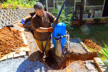 Plumber works on setting up water well pump outside, enhancing in residential area during works day