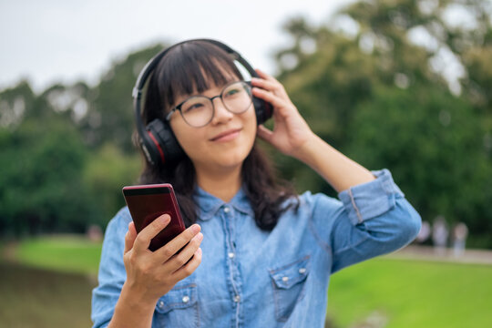 Young woman listening to music outdoors with headphones.
