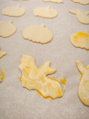 Brushing halloween bat shaped cookies with egg yolk on baking paper