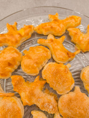 Halloween cookies shaped like bats, pumpkins, and ghosts resting on glass plate