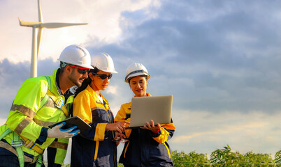Fototapeta premium Male and female engineers team walk together wind farm standing tall against cloudy sky sharing ideas about renewable energy from the earth reviewing plans and collecting data on completed mission.