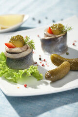 Herring pieces pickled cucumbers served on light blue background