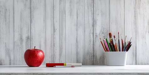 Photo of a white marble countertop with an apple and art supplies on it,