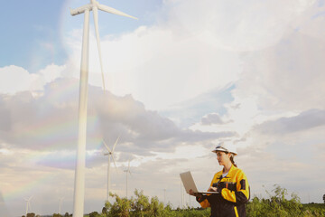Female engineer holding laptop standing checking rotation function integrity tall tower in wide...