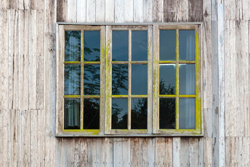 Old country style window in a country house wall, black separated glass.